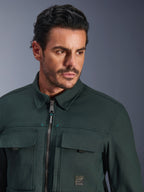 Alpinestars Bryon Water Resistant Overshirt en color Dark Emerald, retrato en primer plano de un hombre con esta chaqueta urbana de moto, con textura de lona encerada, cremallera frontal con sutiles detalles en verde azulado, bolsillos tipo cargo en el pecho y parche con el logotipo de la marca.