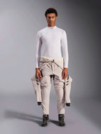Alpinestars ZX Evo V3 Top, manga larga, blanco, capa base de automovilismo usada con un traje de carreras de color claro atado a la cintura y botas de carreras negras, con cuello alto con logo y marca en los hombros, ropa interior técnica profesional resistente a las llamas
