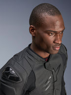 Primer plano de un modelo con la chaqueta de cuero Alpinestars Dusk Airflow, color Black on Black, con amplias zonas de cuero perforado para transpirabilidad, deslizadores de hombro externos DFS y un diseño moderno para conducción deportiva.