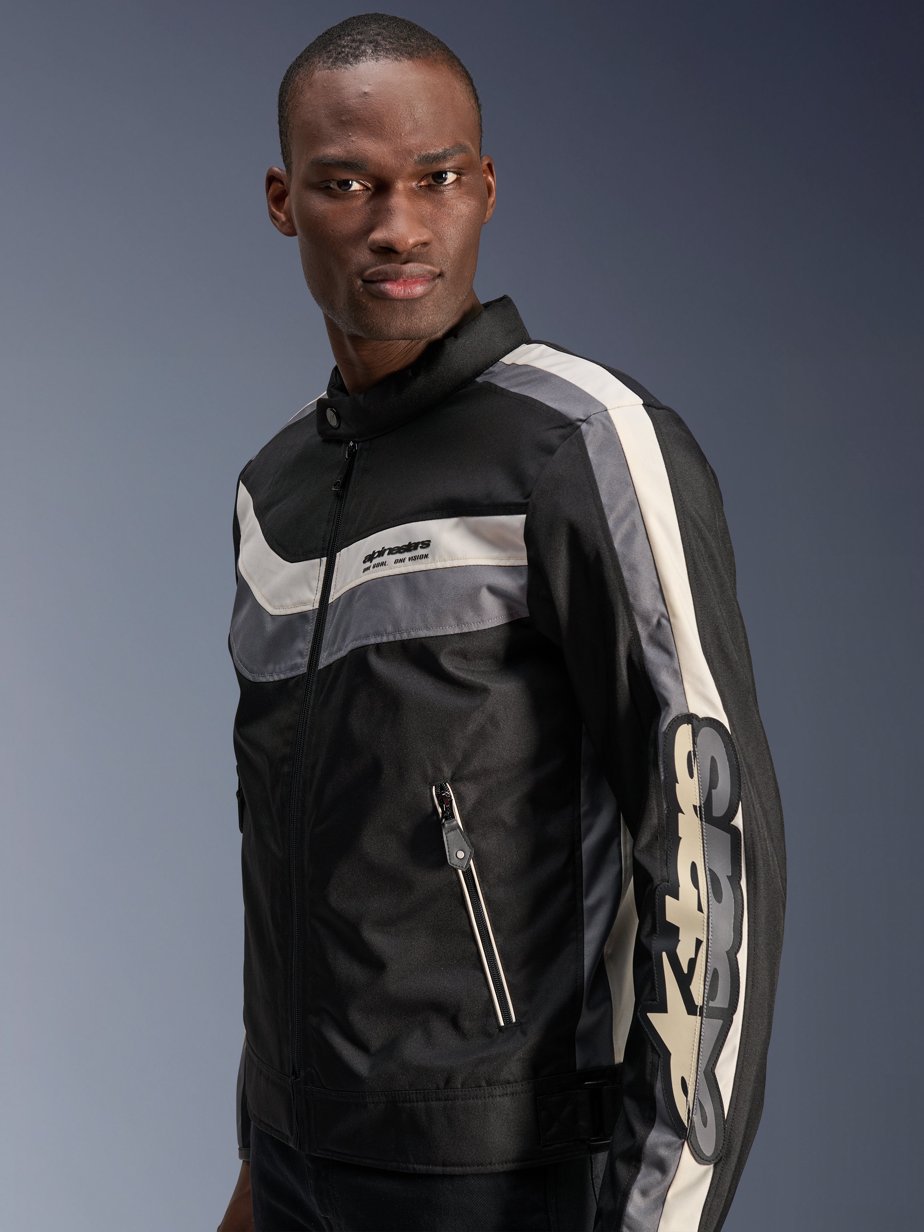 Chaqueta Alpinestars T-Dyno WR, negro, gris oscuro y crudo, chaqueta de moto textil de inspiración vintage con franjas horizontales en el pecho, gran logotipo vertical en la manga y bolsillos frontales con cremallera, equipamiento de carretera urbano