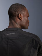 Chaqueta Alpinestars C-1 Air, chaqueta de moto negra, primer plano de la parte posterior mostrando paneles de malla técnica transpirable y logotipo reflectante de Alpinestars en el cuello, equipamiento para conducción urbana