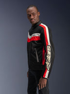 Modelo masculino con la chaqueta Alpinestars T-Dyno Air en negro, rojo brillante y crudo, chaqueta de moto textil de inspiración vintage con paneles de malla 3D, rayas llamativas en rojo y blanco hueso, y logotipo de Alpinestars destacado en la manga