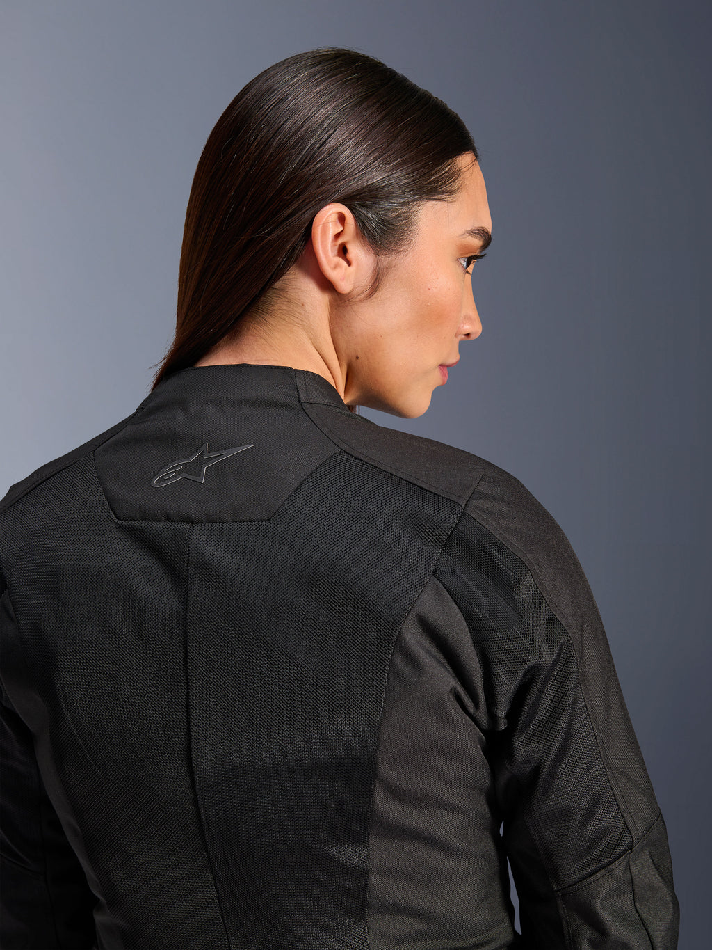 Chaqueta Alpinestars Stella C-1 Air para mujer, chaqueta de moto textil, negra, vista trasera en primer plano que muestra paneles de ventilación de malla técnica y un logotipo de estrella reflectante en la parte superior de la espalda, equipamiento moderno para conducción urbana