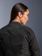 Chaqueta Alpinestars Stella C-1 Air para mujer, chaqueta de moto textil, negra, vista trasera en primer plano que muestra paneles de ventilación de malla técnica y un logotipo de estrella reflectante en la parte superior de la espalda, equipamiento moderno para conducción urbana
