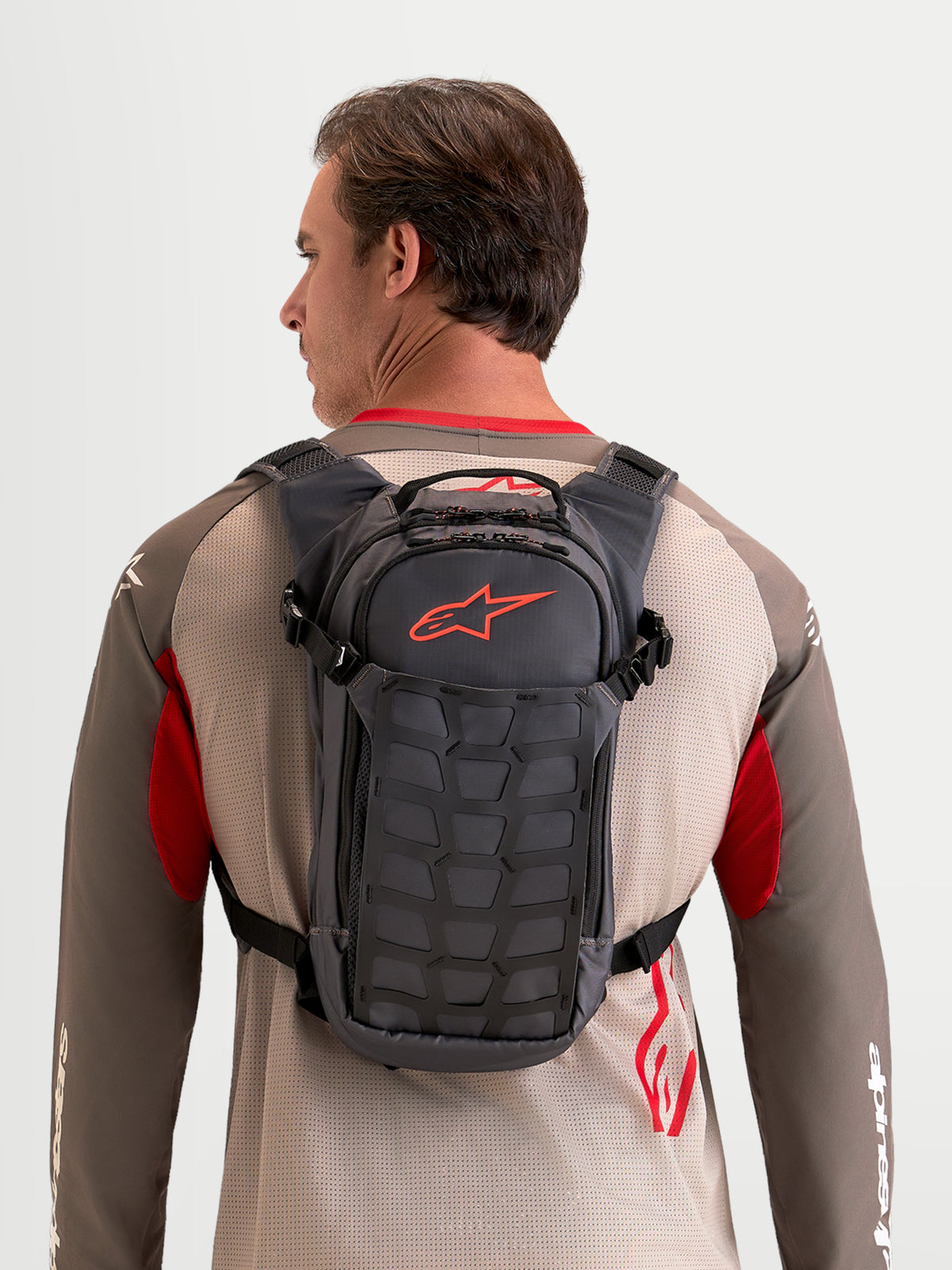 Alpinestars Mochila AT-9, mochila de motocross y uso diario, color gris oscuro y marrón, vista trasera en modelo