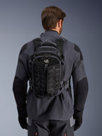 Mochila Alpinestars AT-15, mochila de moto para aventura, Negro Deep Gray, llevada por una persona sobre una chaqueta técnica de moto gris, vista trasera con el logotipo 'ALL TERRA', diseño ergonómico con paneles texturizados reforzados y correas seguras.