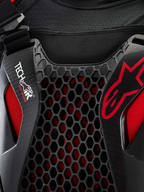 Alpinestars Tech-Air® Off-Road Sistema De Airbag, detalle en primer plano del sistema de airbag para moto off-road, negro y rojo, con protección de pecho de nido de abeja Nucleon CELL, logotipo Tech-Air y chasis de malla elástica transpirable