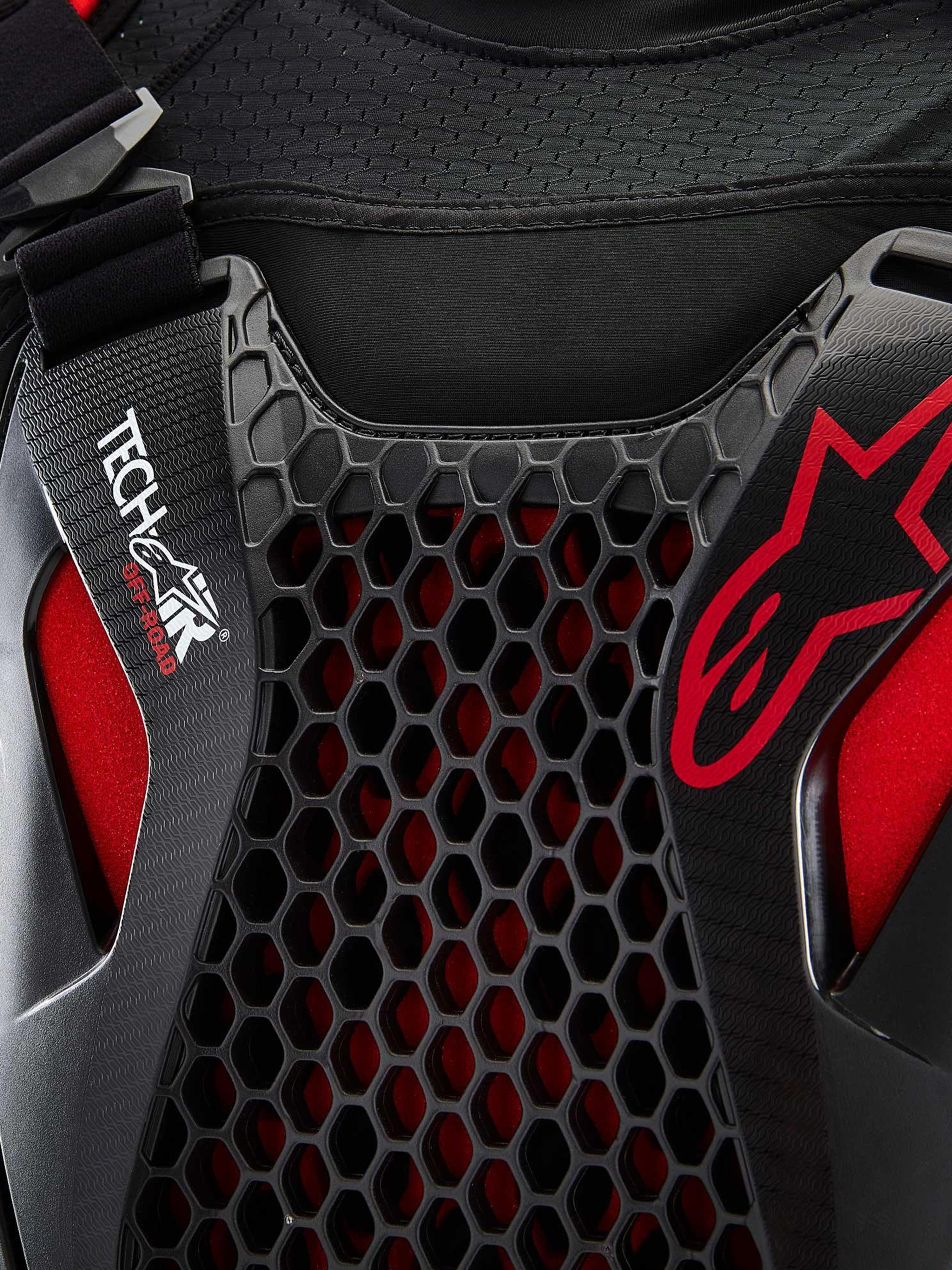 Alpinestars Tech-Air® Off-Road Sistema De Airbag, detalle en primer plano del sistema de airbag para moto off-road, negro y rojo, con protección de pecho de nido de abeja Nucleon CELL, logotipo Tech-Air y chasis de malla elástica transpirable