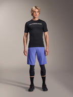 Alpinestars A-Aria Lite Short in Baja Blue, Men's MTB Shorts, worn with a black short-sleeve jersey and protective knee guards, featuring laser perforations for ventilation, mountain bike performance gear