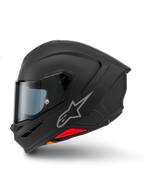 Casco Alpinestars S-R7 Solid, casco integral de moto, negro mate, vista de perfil lateral, con el logotipo plateado de Astars en el lateral, diseño aerodinámico con alerón integrado y ventilaciones en la mentonera, y detalles en rojo y naranja en la base.
