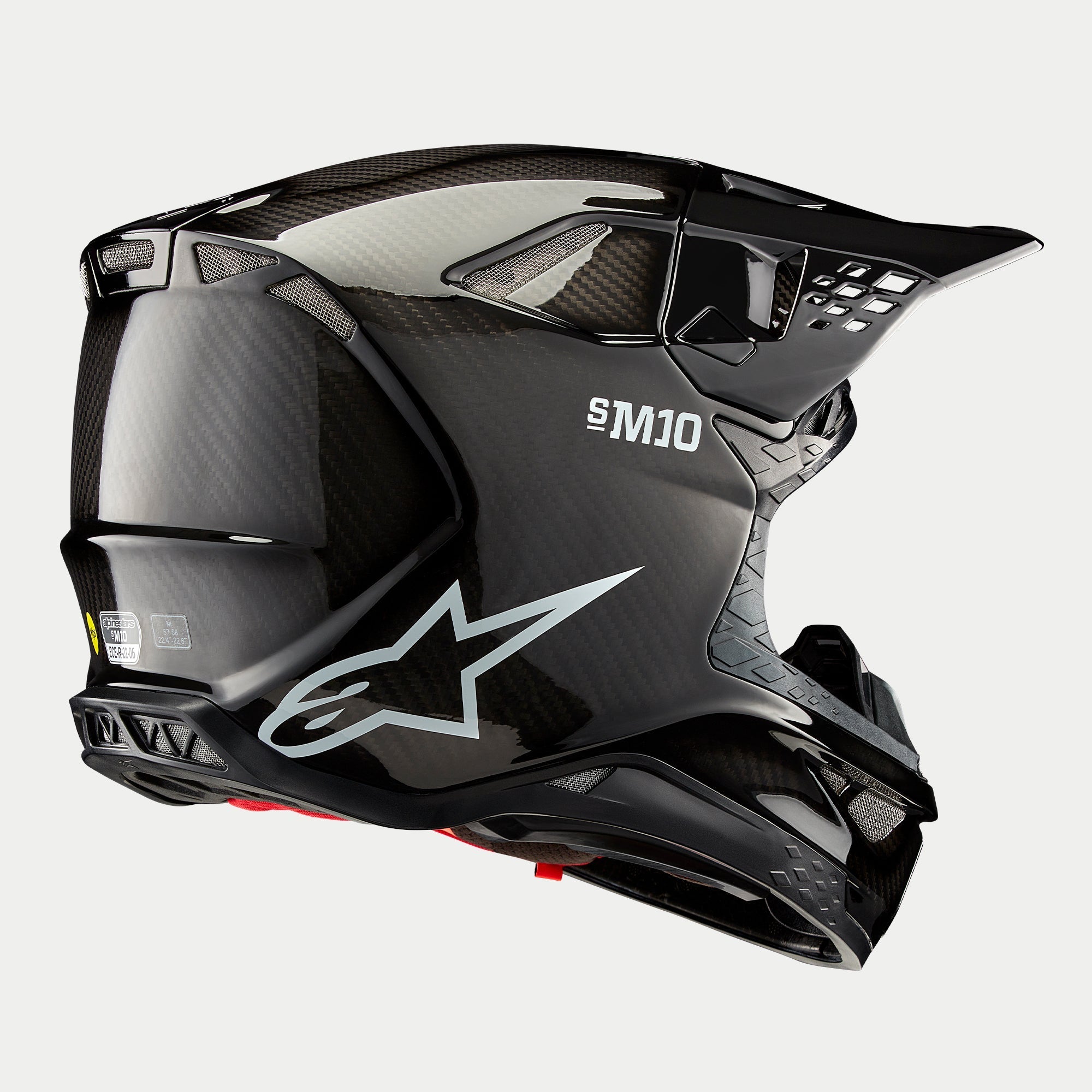 Casco Alpinestars Supertech M10 Solid, casco de motocross, acabado de carbono negro brillante, con el logotipo blanco de Astars y la marca S-M10, calota aerodinámica con tejido de fibra de carbono visible y múltiples puertos de ventilación