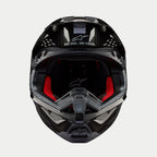 Casco Alpinestars Supertech M10 Solid, casco de motocross, carbono negro brillante, vista frontal que muestra el forro interior rojo, calota de fibra de carbono y el eslogan «ONE GOAL. ONE VISION.» en el área de la visera