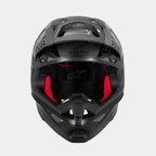 Casco Alpinestars Supertech M10 Fame ECE 22.06, casco de motocross, negro carbono mate y brillante, vista frontal con acolchado interior rojo visible, carcasa de fibra de carbono aerodinámica, diseño ventilado para carreras todoterreno