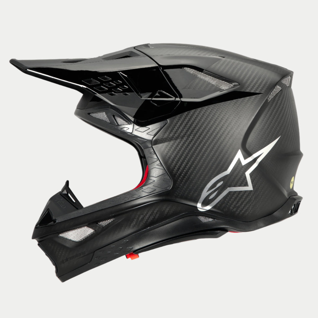 Casco Alpinestars Supertech M10 Fame ECE 22.06, vista de perfil lateral, acabado en carbono negro mate y brillante, con tejido de fibra de carbono visible, logotipo de Astars plateado en el lateral, diseño aerodinámico con puertos de ventilación integrados y visera negra