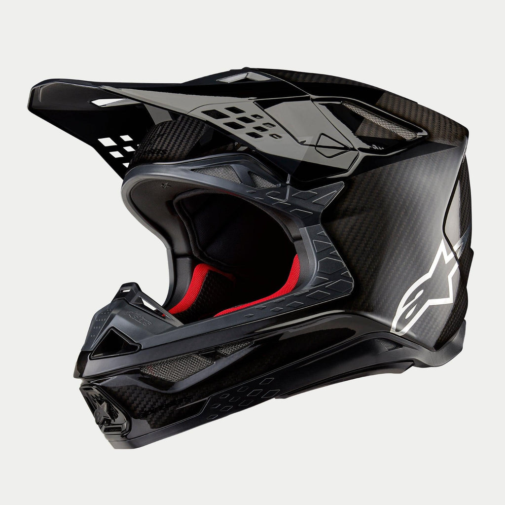 Casco Alpinestars Supertech M10 Fame ECE 22.06, casco de motocross, acabado en carbono negro mate y brillante, con tejido de fibra de carbono visible, logotipo Astar blanco en el lateral y acolchado interior rojo, diseño aerodinámico para off-road