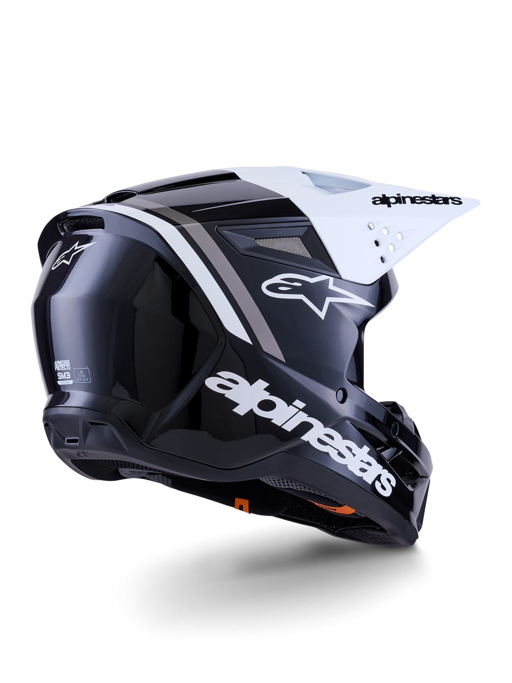 Casco Alpinestars S-M3 Radium, casco de motocross, negro, blanco y gris brillante, vista lateral trasera con visera blanca, con el logotipo de Alpinestars en el lateral y la parte trasera, calota aerodinámica con rejilla de ventilación, diseñado para motocross y enduro
