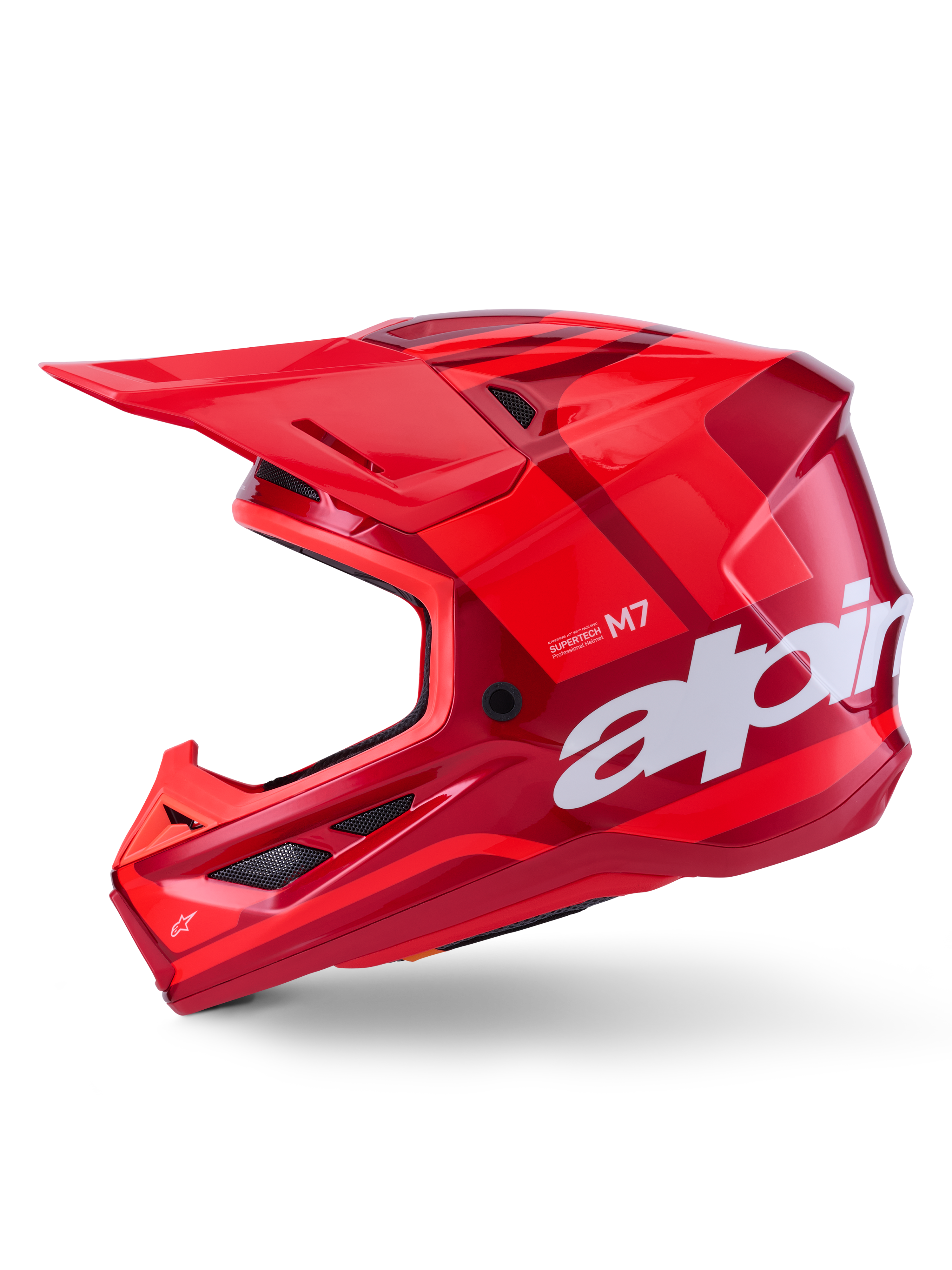 Casco Alpinestars S-M7 Core, color rojo brillante con acentos geométricos, casco de motocross en vista de perfil lateral, calota aerodinámica con puertos de ventilación y logotipos blancos, equipo de competición off-road de alto rendimiento