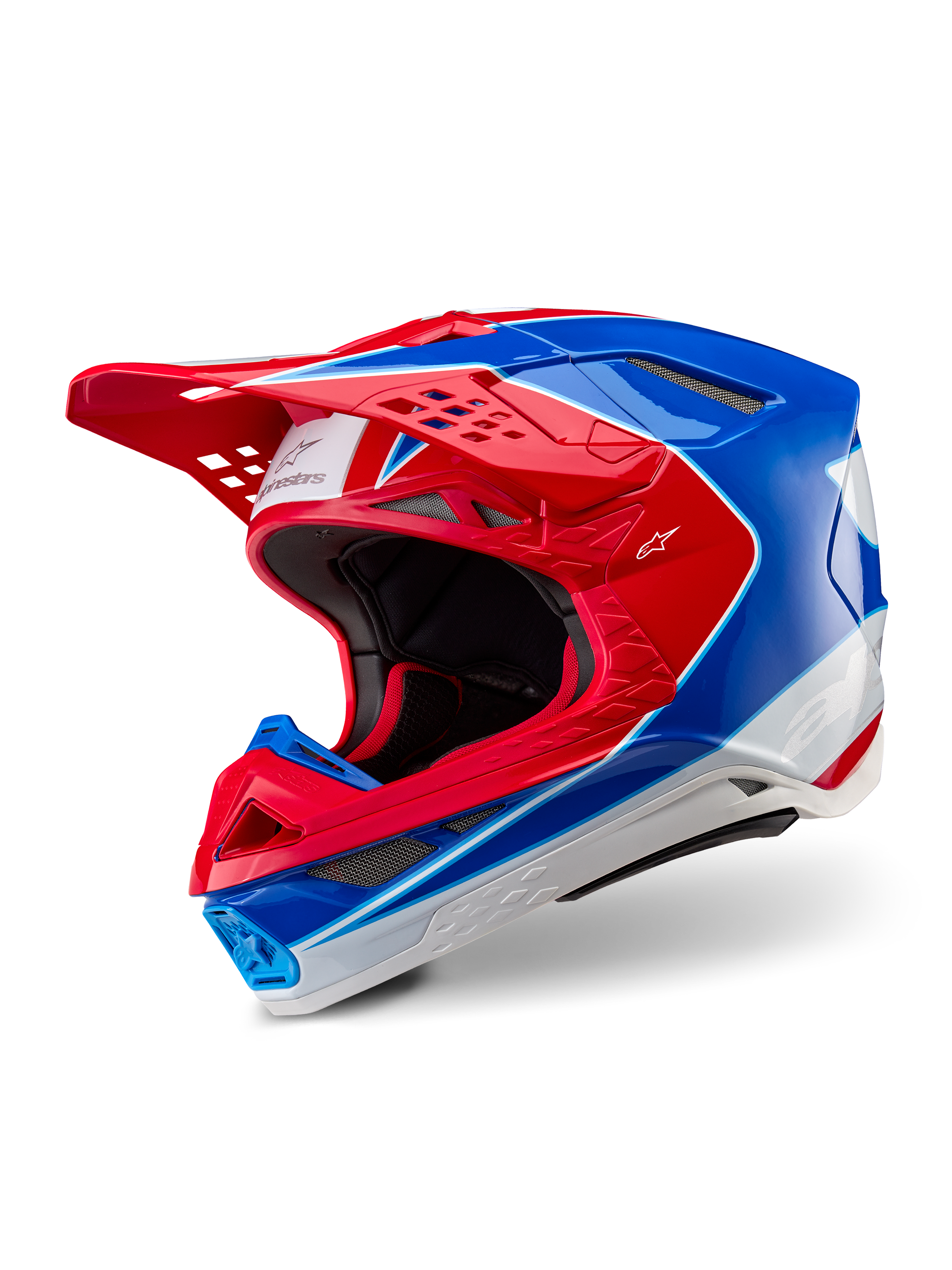 Casco Alpinestars Supertech M10 Aeon, casco de motocross, rojo y azul brillante, vista de tres cuartos que muestra la carcasa aerodinámica con múltiples puertos de ventilación, detalles gráficos en blanco y rojo, logotipo de Alpinestars en la visera y el lateral, equipo profesional de carreras todoterreno