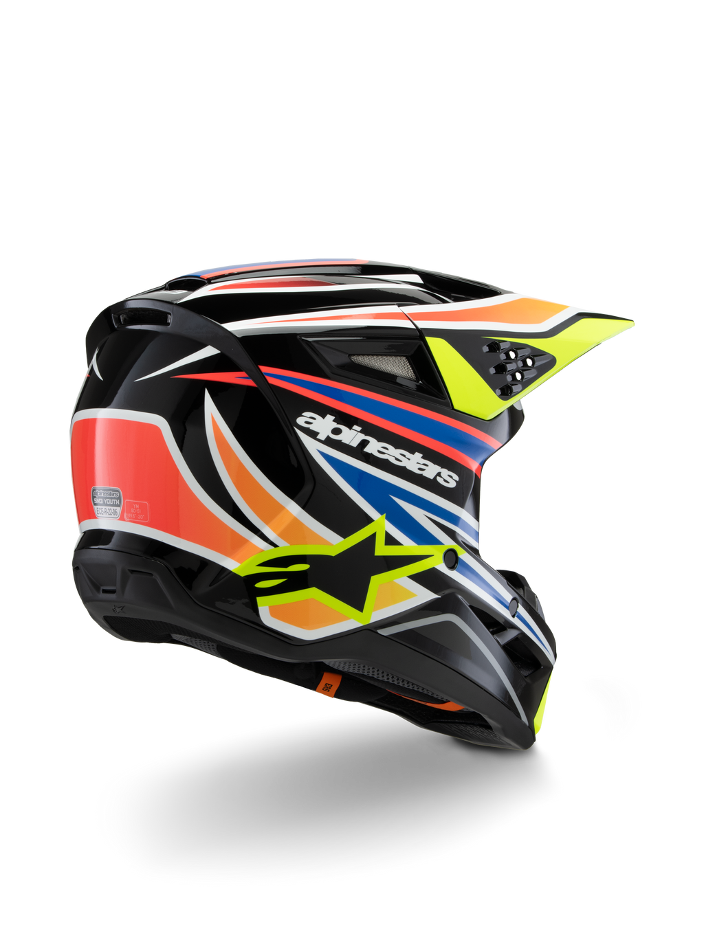 Alpinestars S-M3 Juvenil Wurx, casco de motocross para jóvenes, negro con detalles en naranja vibrante, rojo, azul y amarillo fluorescente, vista trasera en tres cuartos que muestra la carcasa aerodinámica y los orificios de ventilación, acabado brillante con la marca Alpinestars destacada.