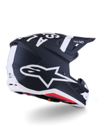 Casco Alpinestars S-M7 Dasher, casco de motocross, negro mate y blanco, vista trasera de tres cuartos con un gran logotipo A-star blanco en el lateral, marca blanca destacada en la parte superior, diseño de calota aerodinámica con puertos de ventilación visibles y acolchado rojo.