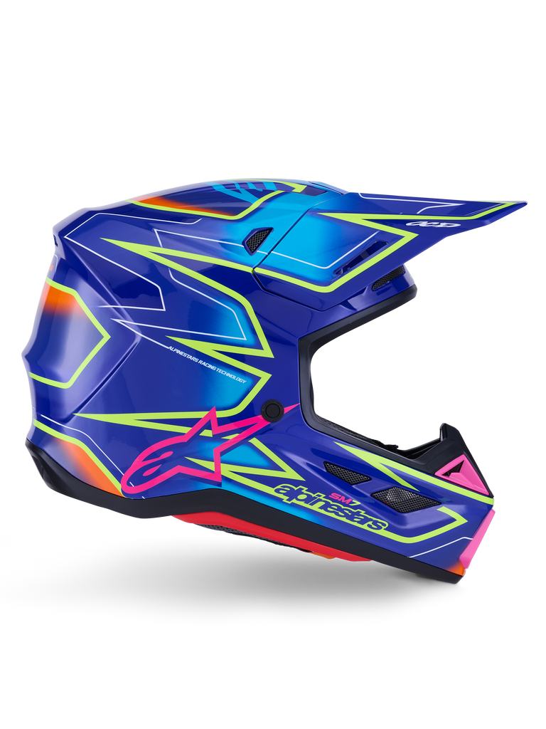 Casco Alpinestars S-M7 Cast, casco de motocross, azul, rosa y amarillo flúor brillante, vista de perfil lateral con llamativos patrones geométricos, logotipo de Alpinestars en rosa y calota aerodinámica ventilada.