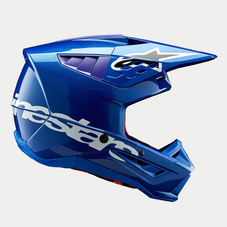 Alpinestars S-M5 Corp Helmet ECE, casco de motocross azul brillante, vista de perfil lateral, logotipo de Alpinestars en color blanco en el lateral, detalles púrpuras en los puertos de ventilación, calota aerodinámica ligera para rendimiento off-road