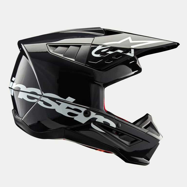 Casco Alpinestars S-M5 Corp, casco de motocross, gris oscuro brillante, vista de perfil lateral con un gran logotipo de Alpinestars en blanco, logotipo de estrella blanca en la visera, elegantes conductos de ventilación aerodinámicos, acabado brillante, protección para carreras off-road