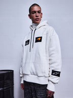 Alpinestars RSRV Rival Hoodie, sudadera blanca con parches negros y naranja, cuello alto incluido, colección streetwear premium, estilo urbano motorsport