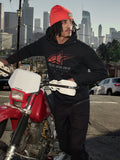 Sudadera con capucha Alpinestars Pulse, negra, sudadera de forro polar con logotipo Astars Combo en rojo y gris, hombre con gorro naranja junto a una motocicleta Honda roja en un entorno urbano, ropa urbana casual de estilo motorsport