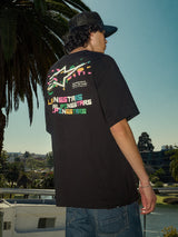 Alpinestars Wild Oversized CSF Tee, camiseta de manga corta, negra, logotipo Astars multicolor vibrante en la espalda, corte de gran tamaño, foto de estilo de vida casual de tipo streetwear con palmeras