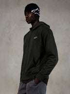 Alpinestars Essentials Ageless Hoodie, Off Black, Male model wearing casual streetwear, dark charcoal stone-washed fleece with a small white star logo, paired with a black Alpinestars beanie and grey pants