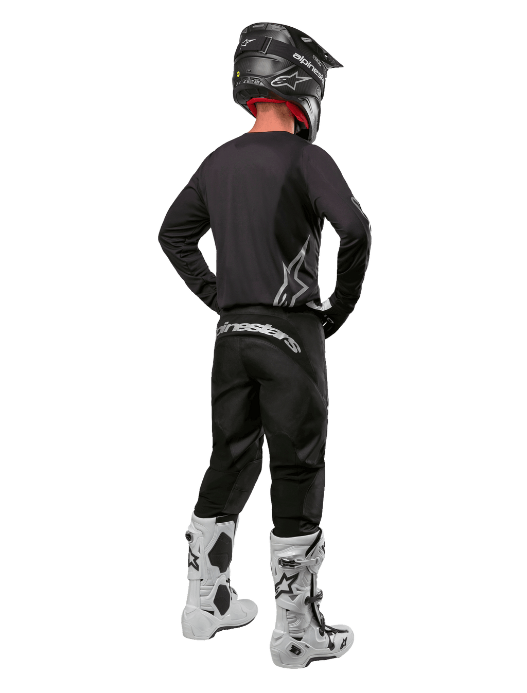Alpinestars 2024 Fluid Graphite Gear Set, piloto de motocross visto desde atrás, jersey y pantalones gris grafito con marca Alpinestars plateada, casco negro y botas de motocross blancas, equipamiento de ajuste deportivo para conducción off-road