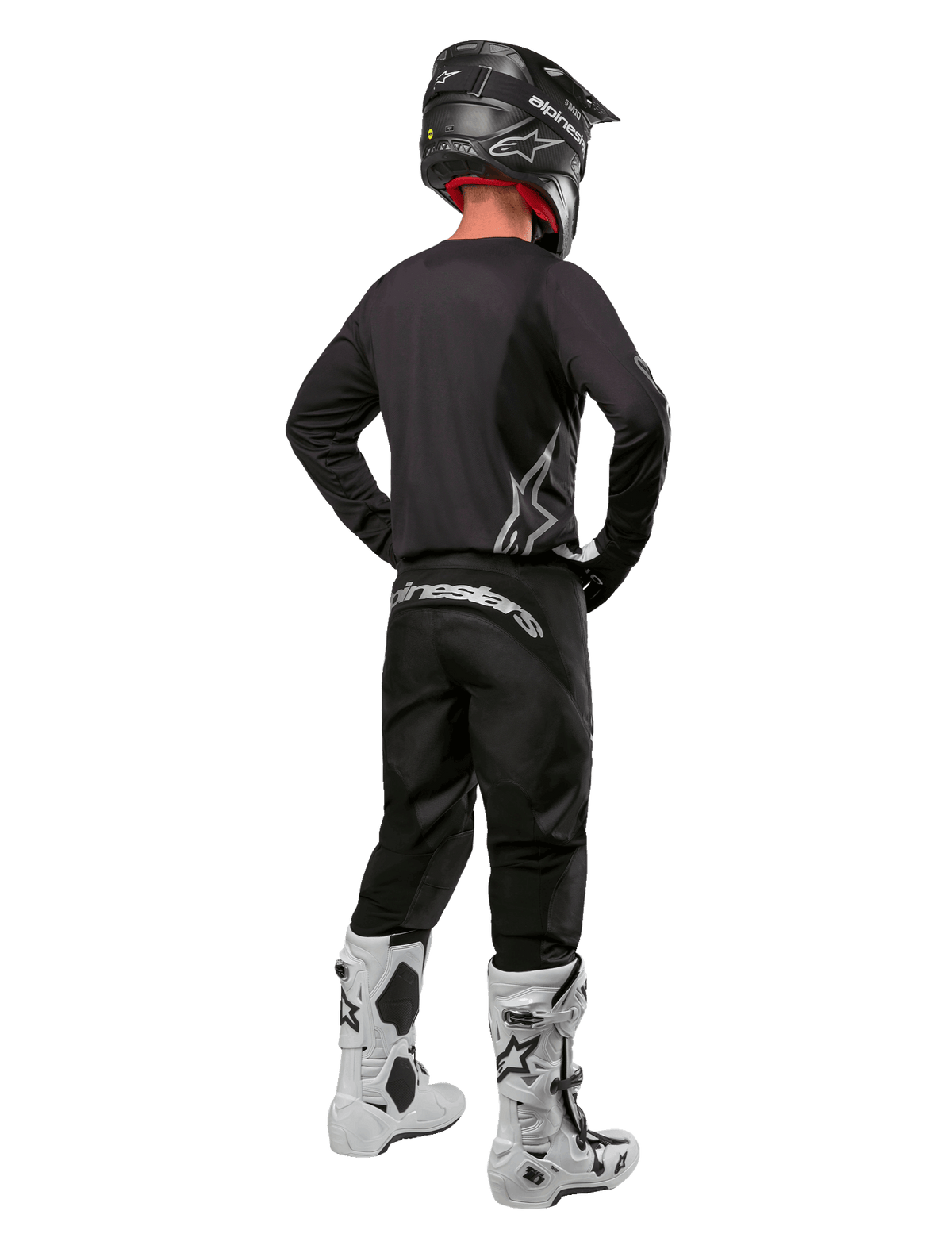 Alpinestars 2024 Fluid Graphite Gear Set, piloto de motocross visto desde atrás, jersey y pantalones gris grafito con marca Alpinestars plateada, casco negro y botas de motocross blancas, equipamiento de ajuste deportivo para conducción off-road
