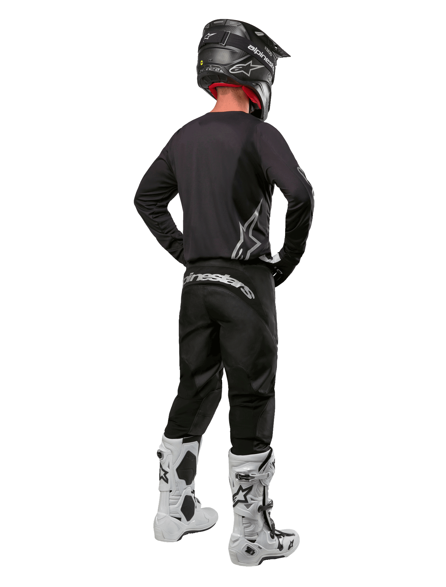 Alpinestars 2024 Fluid Graphite Gear Set, piloto de motocross visto desde atrás, jersey y pantalones gris grafito con marca Alpinestars plateada, casco negro y botas de motocross blancas, equipamiento de ajuste deportivo para conducción off-road