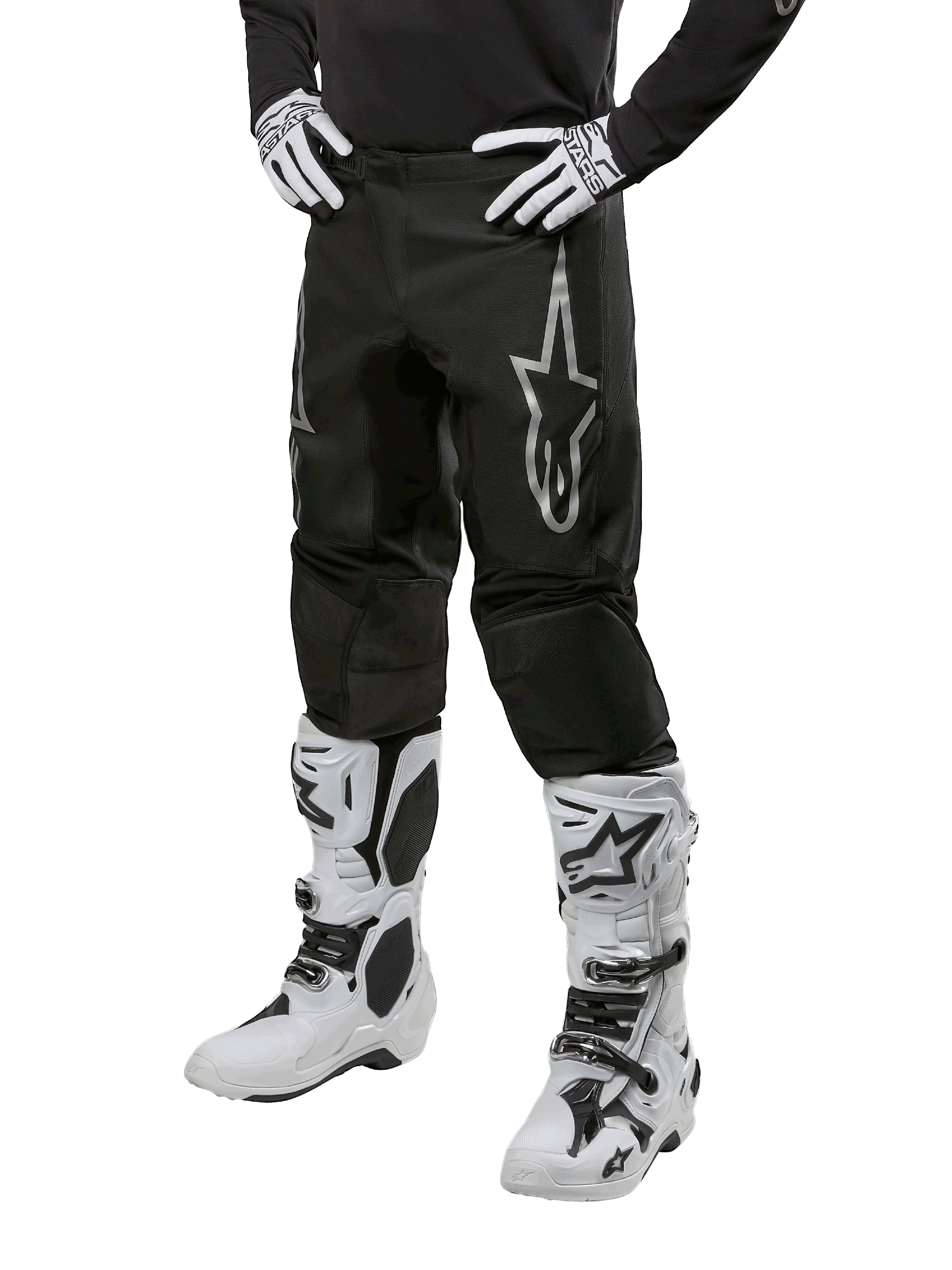 Alpinestars 2024 Fluid Graphite Pants, pantalones de motocross, gris y negro, usados con botas y guantes de motocross en blanco y negro, con un gran logotipo plateado de Alpinestars en el muslo, ajuste deportivo atlético para conducción todoterreno