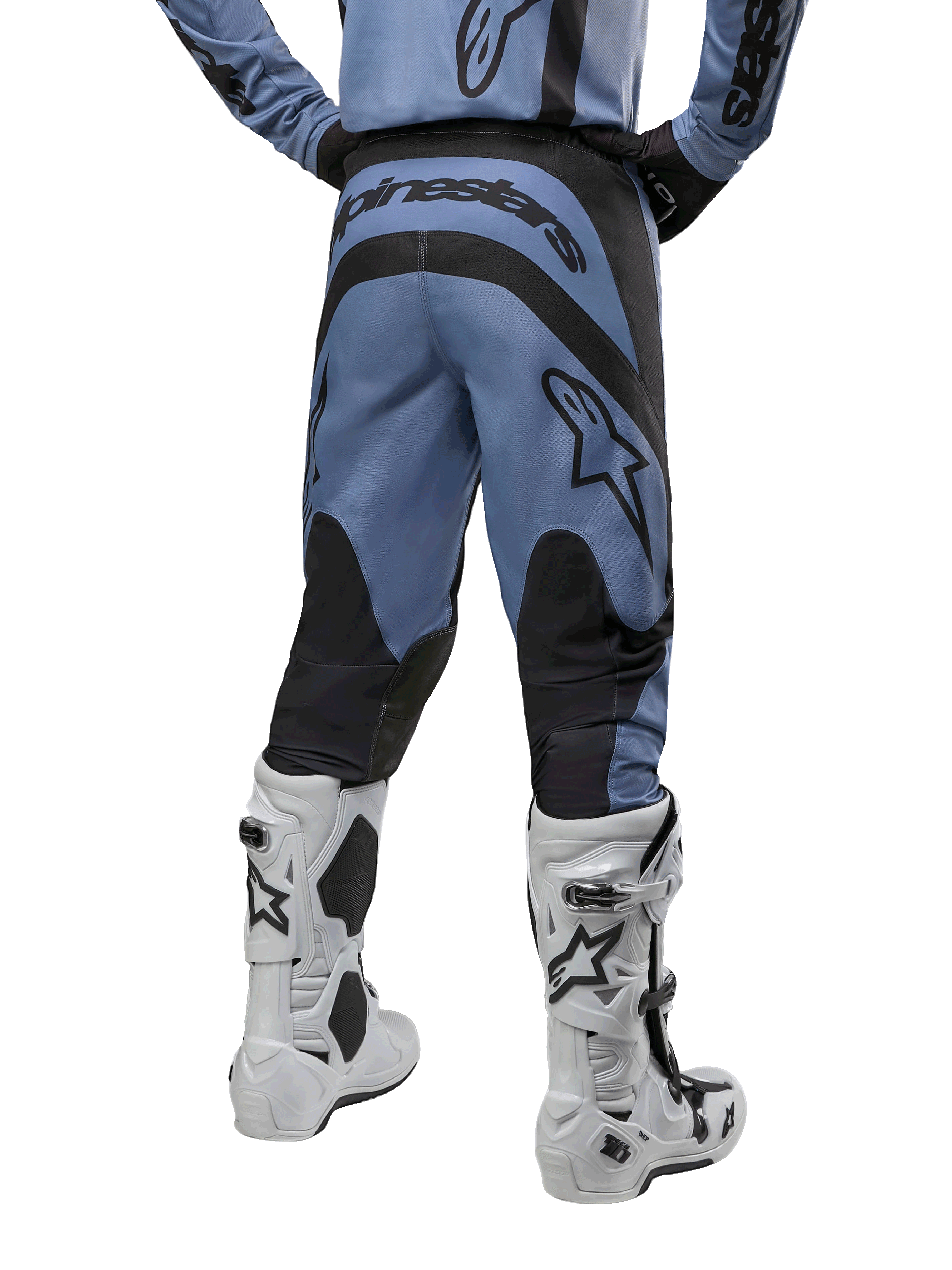 Pantalones Alpinestars Fluid Lurv 2024, pantalones de motocross, azul claro y negro, vista trasera que muestra paneles reforzados negros y logotipo grande de la marca, combinados con botas de motocross blancas y negras, equipamiento de carreras profesional para conducción off-road