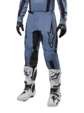 Alpinestars 2024 Fluid Lurv Pants, pantalones de motocross, azul claro y negro, usados con jersey de manga larga a juego y botas de motocross blancas, con un prominente logotipo de estrella negra en el muslo y paneles internos de la rodilla reforzados, vista frontal sobre fondo blanco