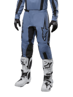 Alpinestars 2024 Fluid Lurv Pants, pantalones de motocross, azul claro y negro, usados con jersey de manga larga a juego y botas de motocross blancas, con un prominente logotipo de estrella negra en el muslo y paneles internos de la rodilla reforzados, vista frontal sobre fondo blanco