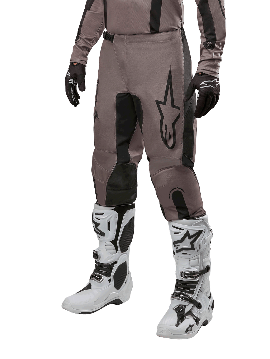Alpinestars 2024 Fluid Lurv Pants, pantalones de motocross, negro barro y negro, con el logo de Alpinestars, usados con guantes negros y botas de motocross blancas, diseño deportivo para carreras todoterreno