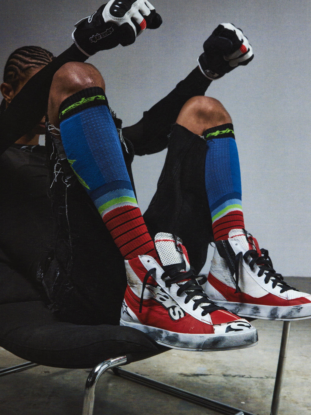 Alpinestars RSRV Legacy Shoe, zapatillas altas rojas, blancas y negras con cordones negros, estilo urbano premium, persona sentada con calcetines coloridos a rayas