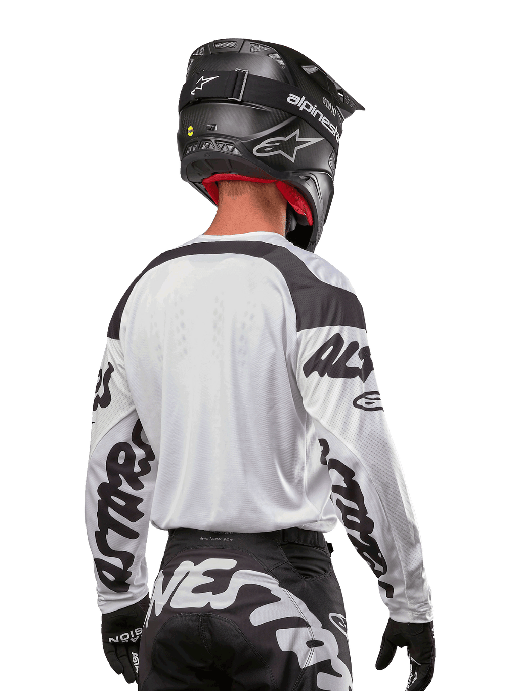 Jersey Alpinestars Racer Hana 2024, blanco y negro, vista posterior que muestra el ajuste ergonómico y la llamativa marca en las mangas, combinado con un casco de motocross negro y pantalones a juego en blanco y negro, equipamiento de alto rendimiento para conducción off-road