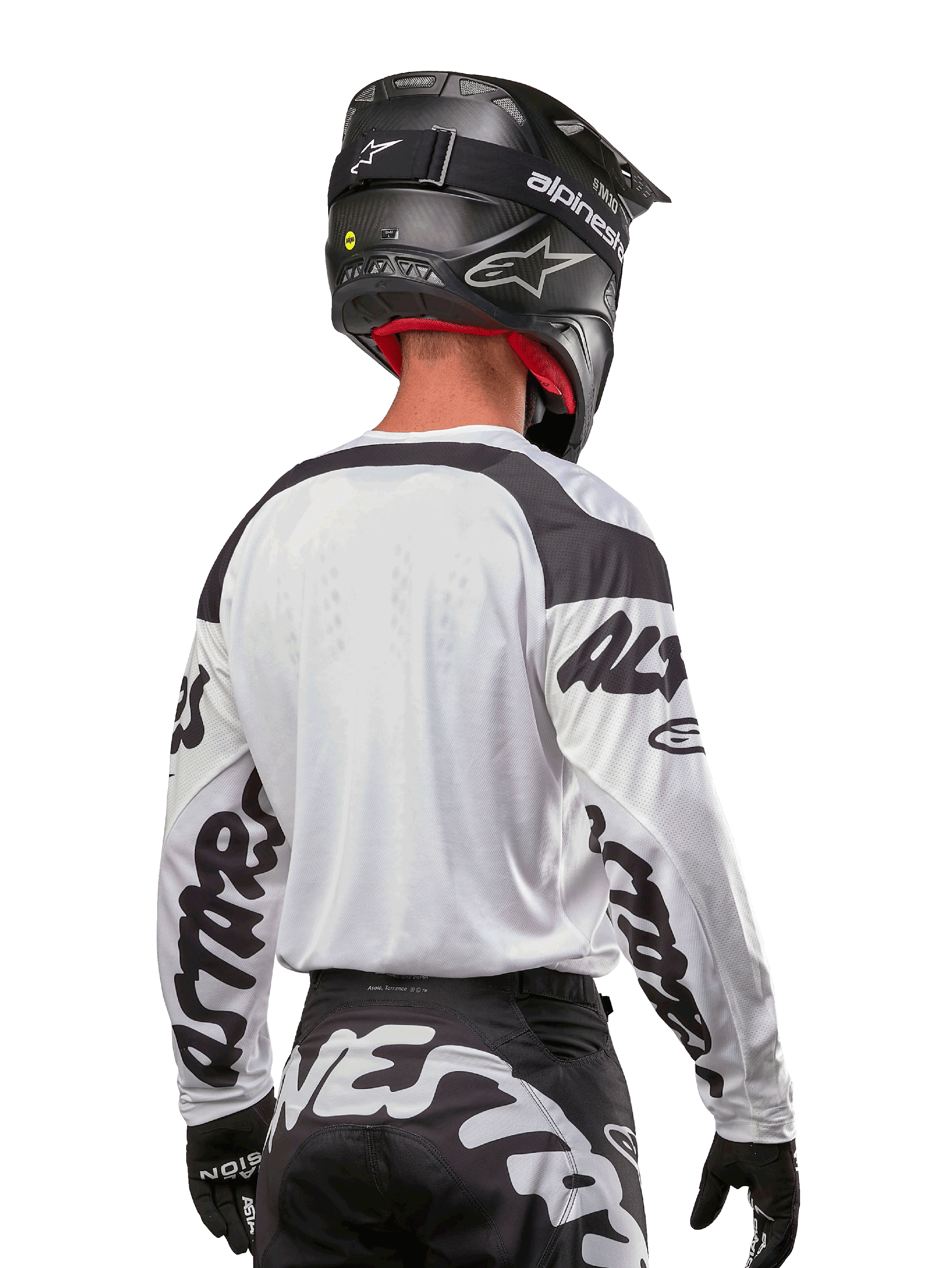 Jersey Alpinestars Racer Hana 2024, blanco y negro, vista posterior que muestra el ajuste ergonómico y la llamativa marca en las mangas, combinado con un casco de motocross negro y pantalones a juego en blanco y negro, equipamiento de alto rendimiento para conducción off-road