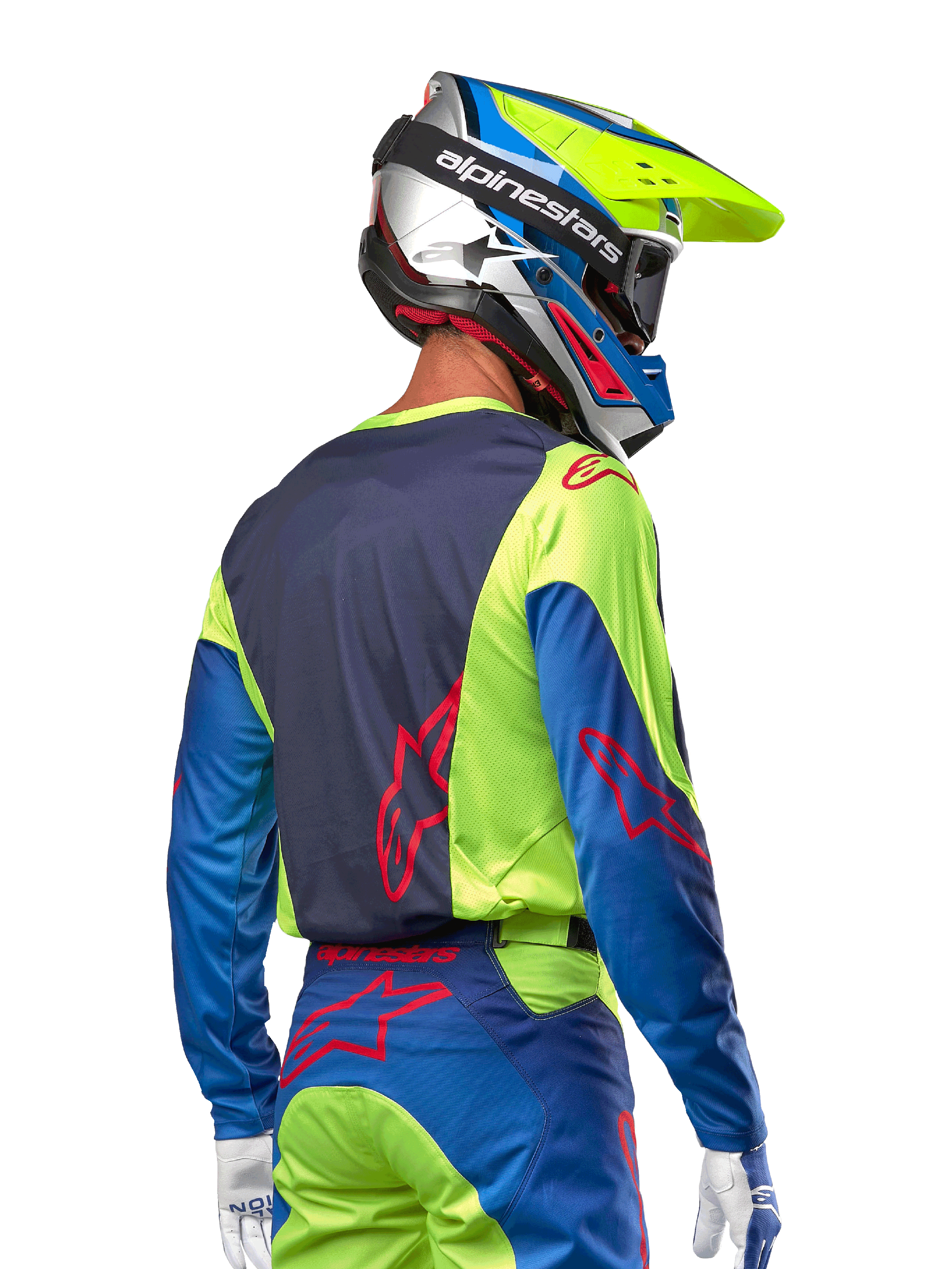 Piloto de motocross vistiendo el jersey Alpinestars 2024 Racer Hoen en amarillo flúor y azul marino, con un logotipo de estrella roja en la espalda, pantalones de motocross a juego y casco de carreras coordinado, vista trasera que muestra el diseño ergonómico para rendimiento todoterreno.