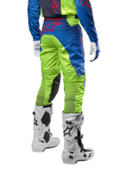 Alpinestars Racer Hoen Pants 2024, pantalones de motocross, amarillo flúor y azul Night Navy, vista trasera, con el logotipo de Alpinestars en rojo, combinados con jersey a juego, guantes blancos y botas de motocross blancas, tejido duradero para carreras off-road