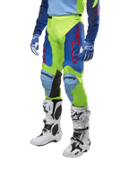 Alpinestars Racer Hoen Pants 2024, pantalones de motocross, amarillo flúor y azul noche navy, con logotipos de estrellas rojas y paneles internos negros en las rodillas, usados con jersey a juego y botas de motocross blancas, equipo de alto rendimiento para carreras todoterreno