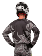 Alpinestars 2024 Racer Tactical Jersey, jersey de motocross, Cast Gray Camo Magnet, vista posterior que muestra el patrón de camuflaje gris y negro, usado con pantalones a juego y un casco blanco y negro, equipamiento profesional de carreras todoterreno
