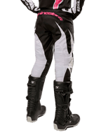 Alpinestars Stella Fluid 2024 para mujer, pantalones de motocross en negro y blanco, vista trasera con paneles blancos en las piernas y logotipo rosa en la cintura, combinados con botas Tech 3 negras, equipamiento duradero para competiciones off-road