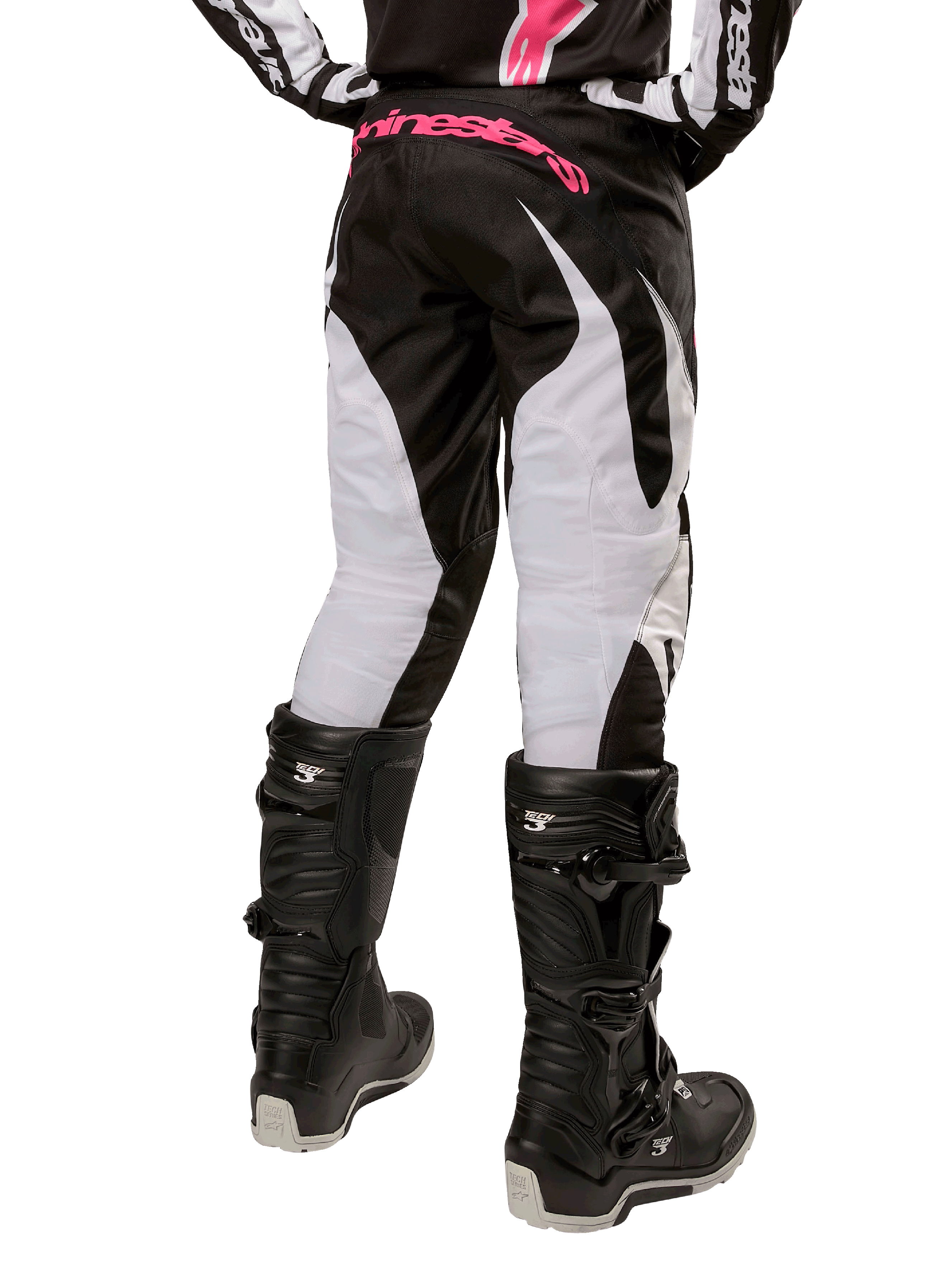 Alpinestars Stella Fluid 2024 para mujer, pantalones de motocross en negro y blanco, vista trasera con paneles blancos en las piernas y logotipo rosa en la cintura, combinados con botas Tech 3 negras, equipamiento duradero para competiciones off-road