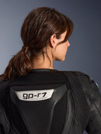Traje de cuero de 2 piezas Alpinestars Stella GP-R7, negro, vista de primer plano de la parte posterior con el logotipo GP-R7 en la joroba aerodinámica, paneles de cuero en acordeón en los hombros, construcción premium de nivel de competición para mujer.