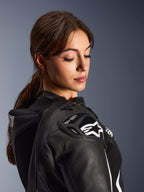 Mujer con el traje de cuero de 2 piezas Alpinestars Stella GP-R7, primer plano del hombro de cuero negro con protección DFS RR y logo de estrella blanca, que incluye la joroba aerodinámica integrada y detalles perforados.